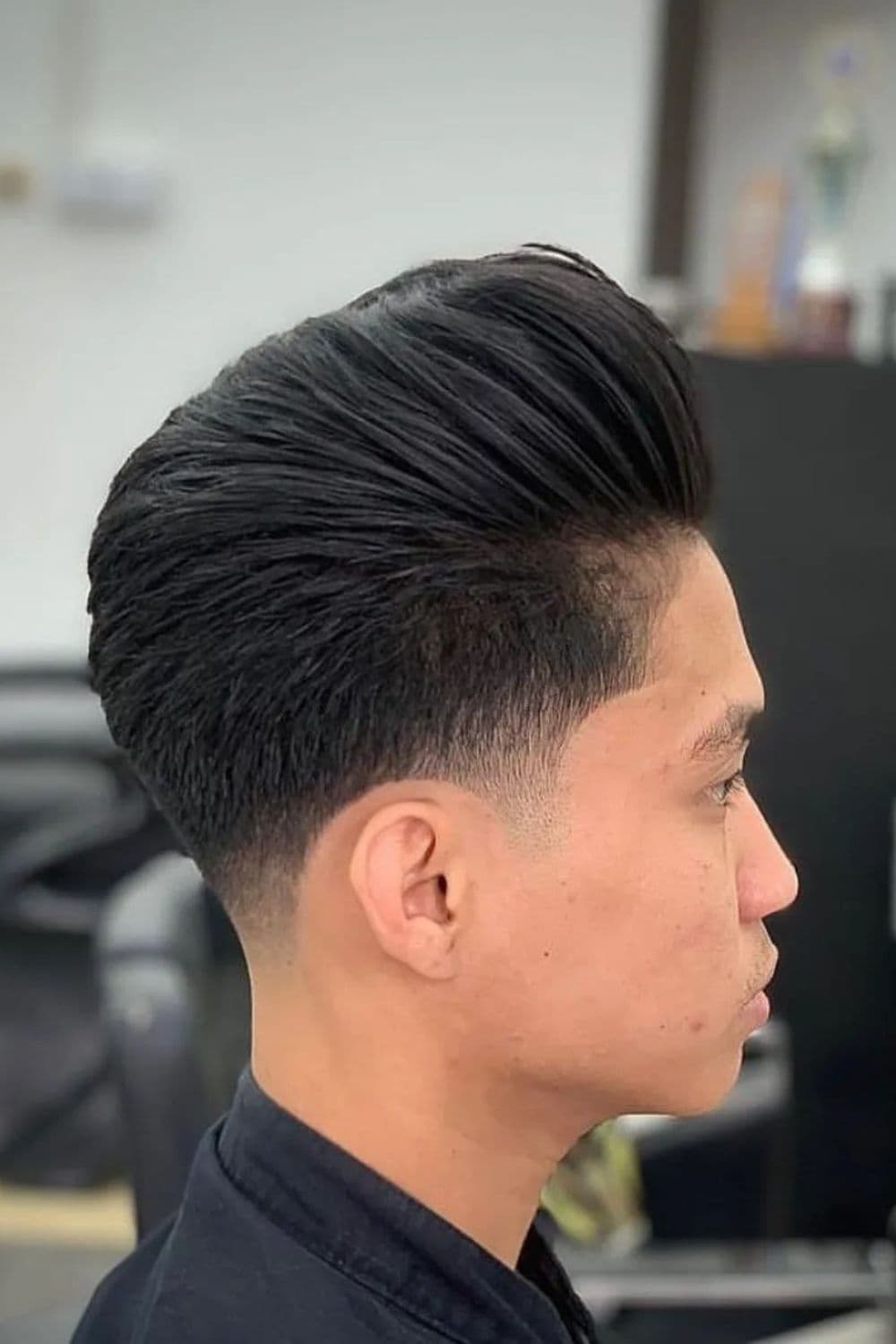 Side view of a man with pompadour with low taper fade.