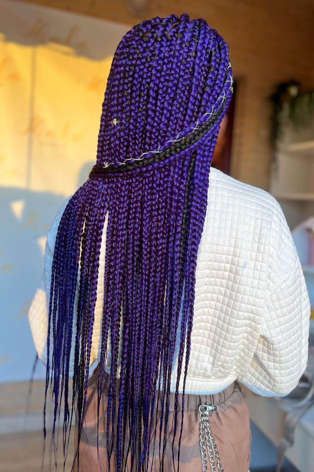 A person with purple box braids with thread and cuffs.