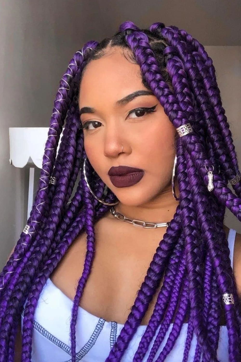 A woman with purple box braids and hair rings.