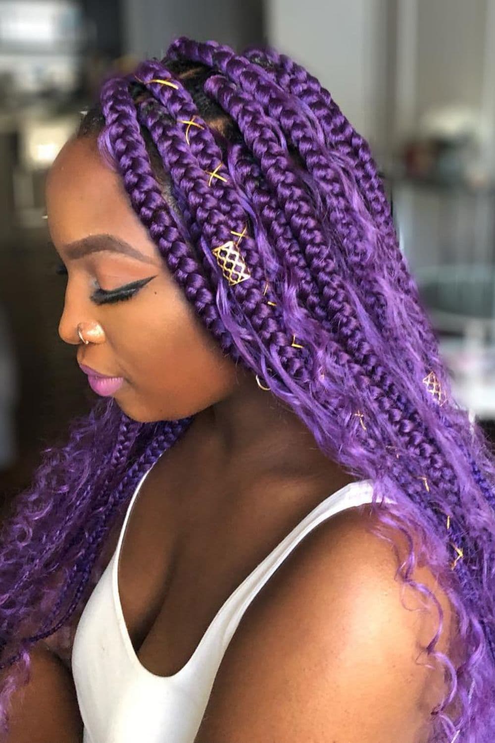 Side view of a woman with purple goddess braids with cuffs and thread.