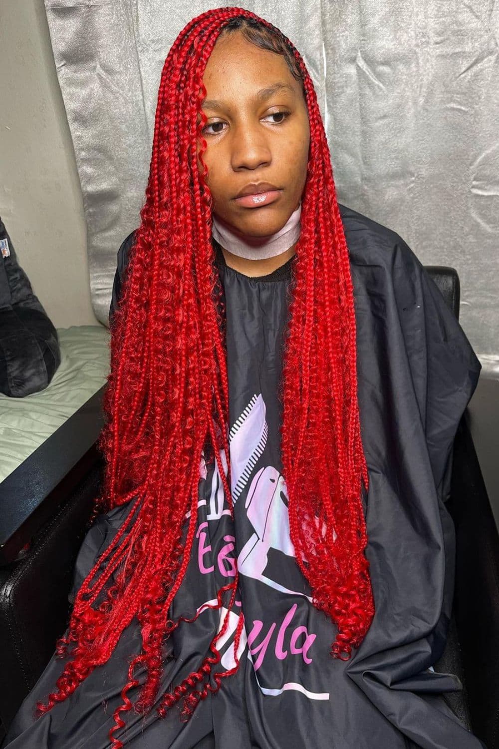 A woman with red knotless goddess braids.