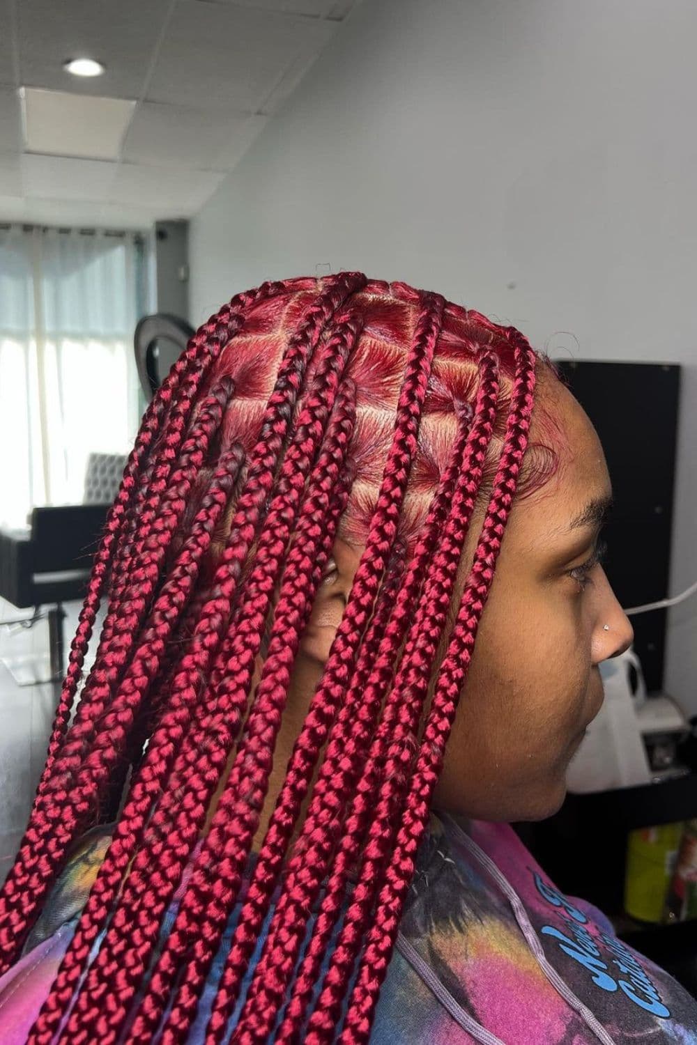 Side view of a woman with red medium knotless braids.
