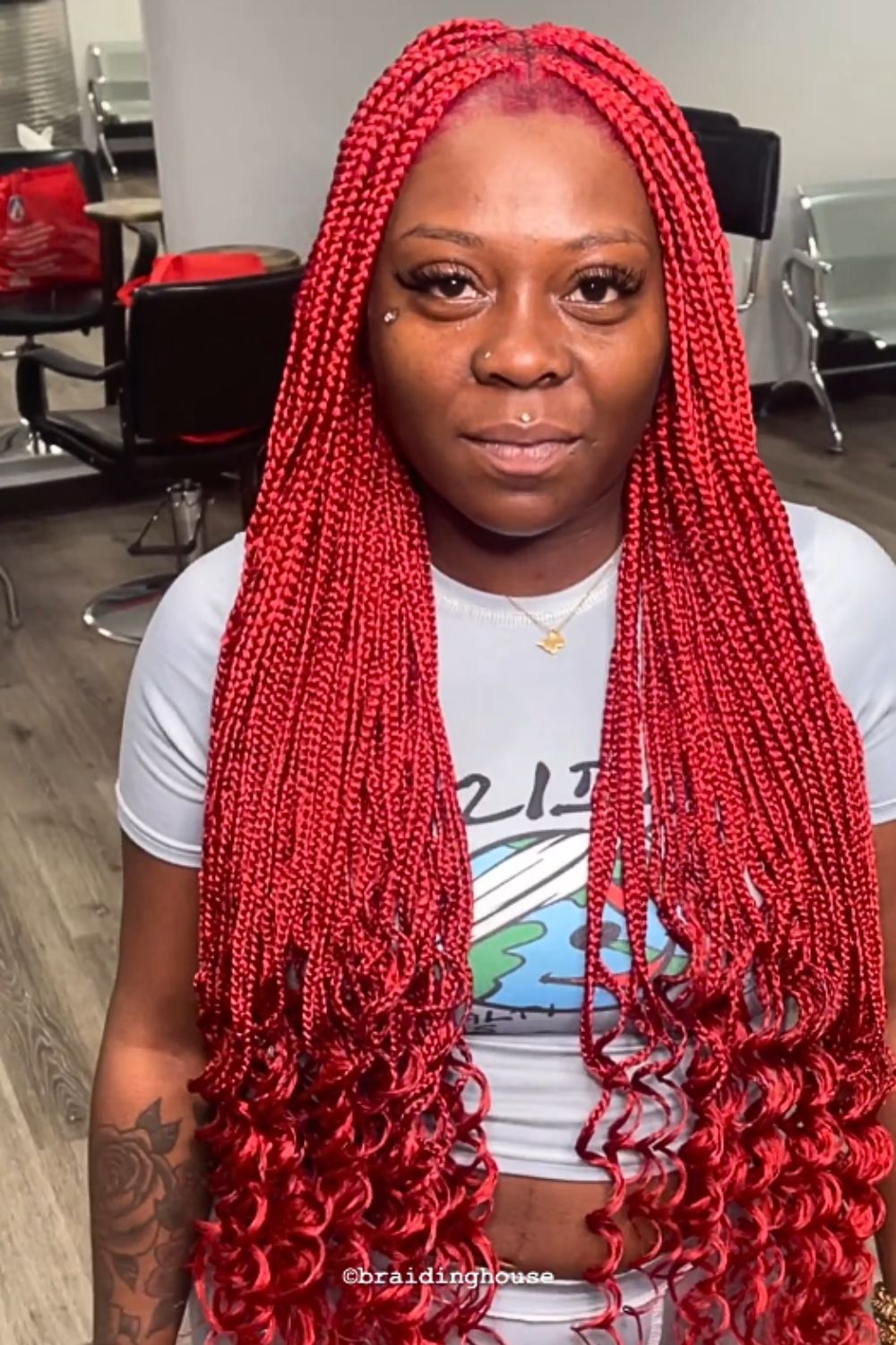 A woman wearing a white crop top with red mini braids with curly ends.
