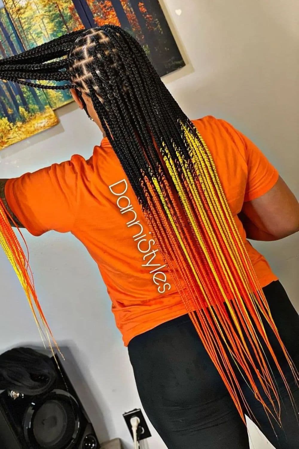 A person with long red, orange, and yellow ombre braids.