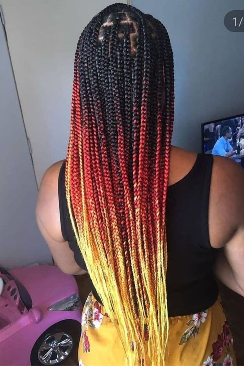 A woman with red to orange to yellow ombre knotless braids.