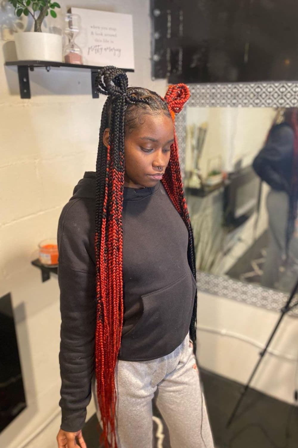 A woman wearing a black sweater with red and black knotless braids.