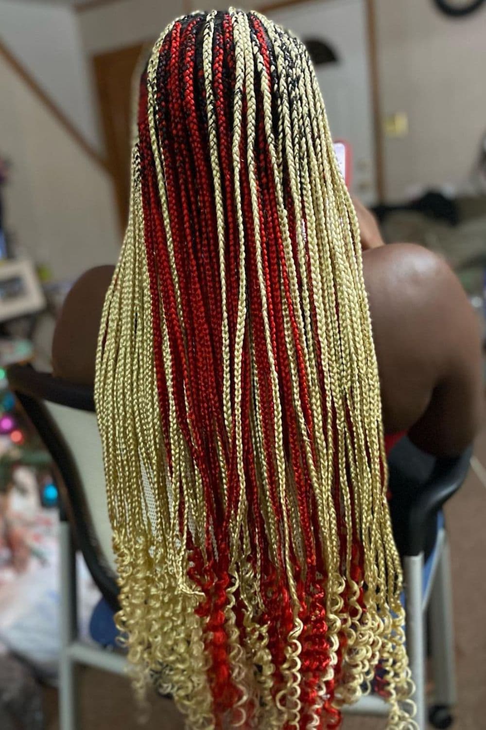 A woman with red and blonde knotless braids with curly ends.