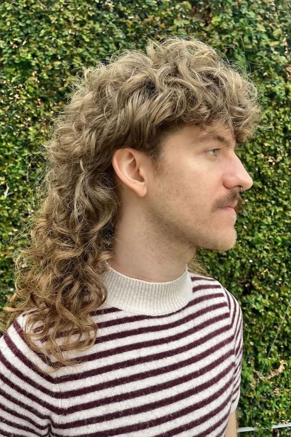 Side view of a man with retro 80s curly blonde mullet.
