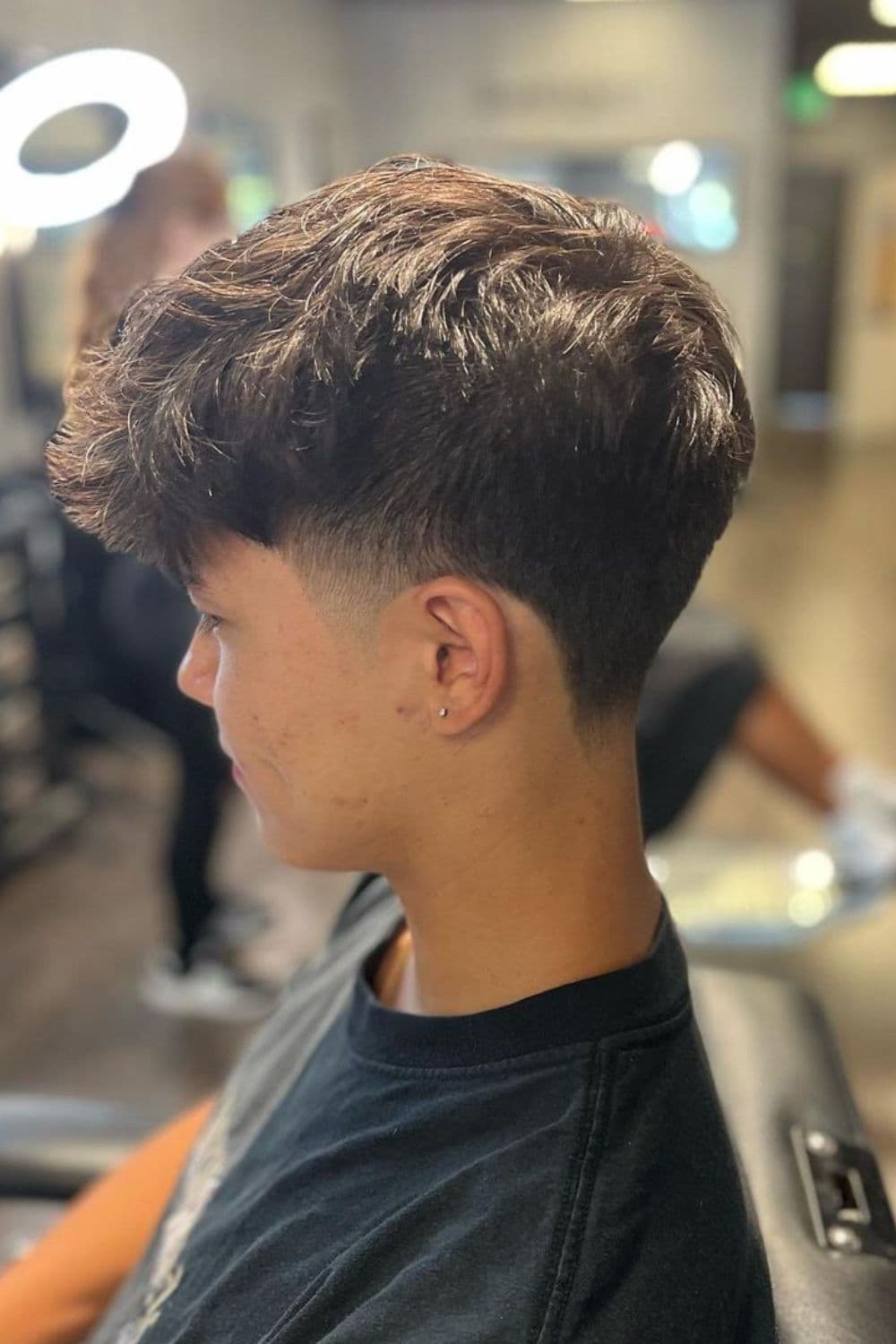 Side view of a man with shaggy low taper fade.