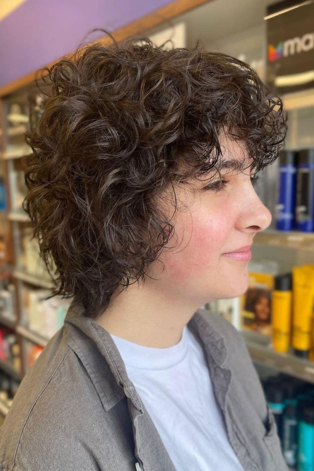 Side view of a woman with short curly wolf cut.