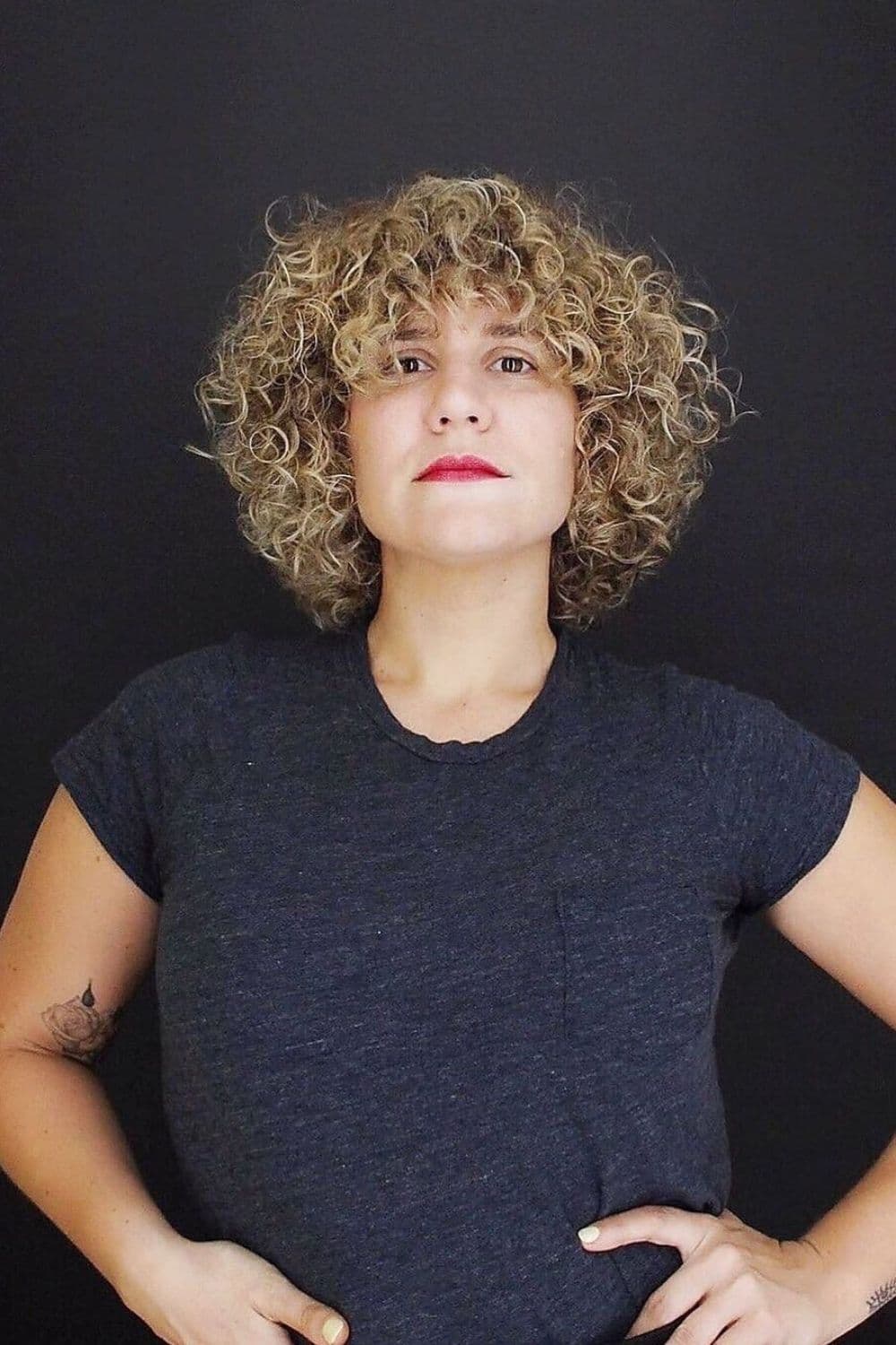 A woman with a curly short layered cut and curly bangs.