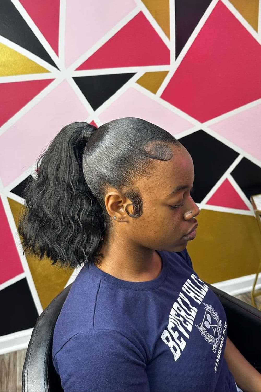 Side view of a woman in blue t-shirt with a black short ponytail.