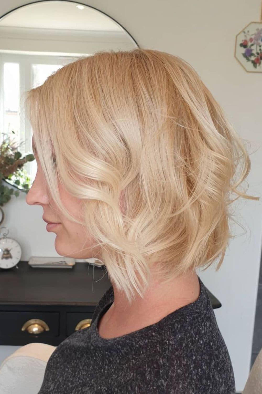 Side view of a woman with short wavy blonde bob with long edgy layers.