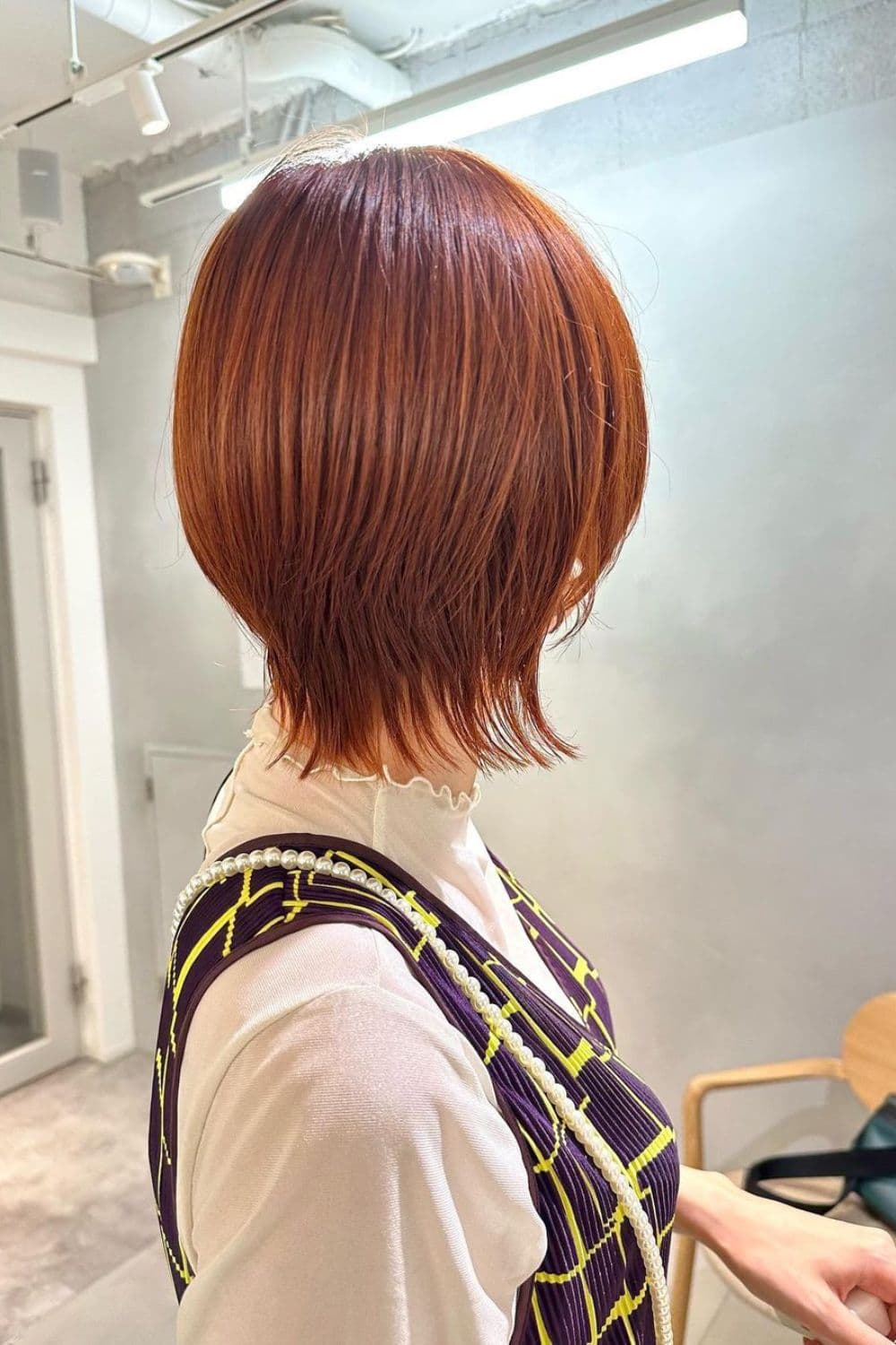 Back of a woman with a straight, orange short wolf cut.
