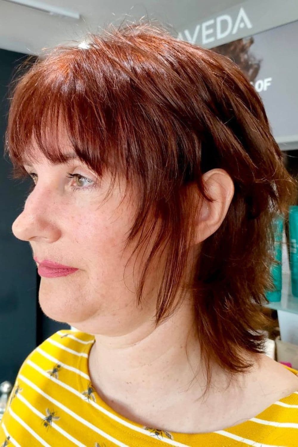 Side view of a woman with a red short wolf cut with choppy layers.