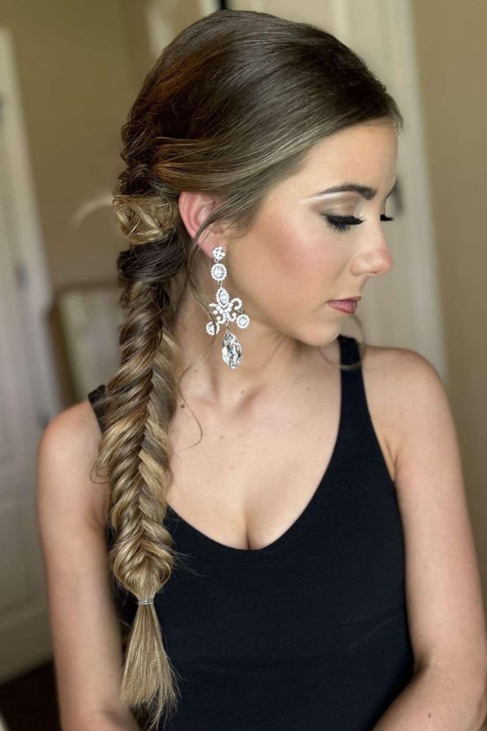 Side view of a woman wearing black tank top with a side fishtail braid.