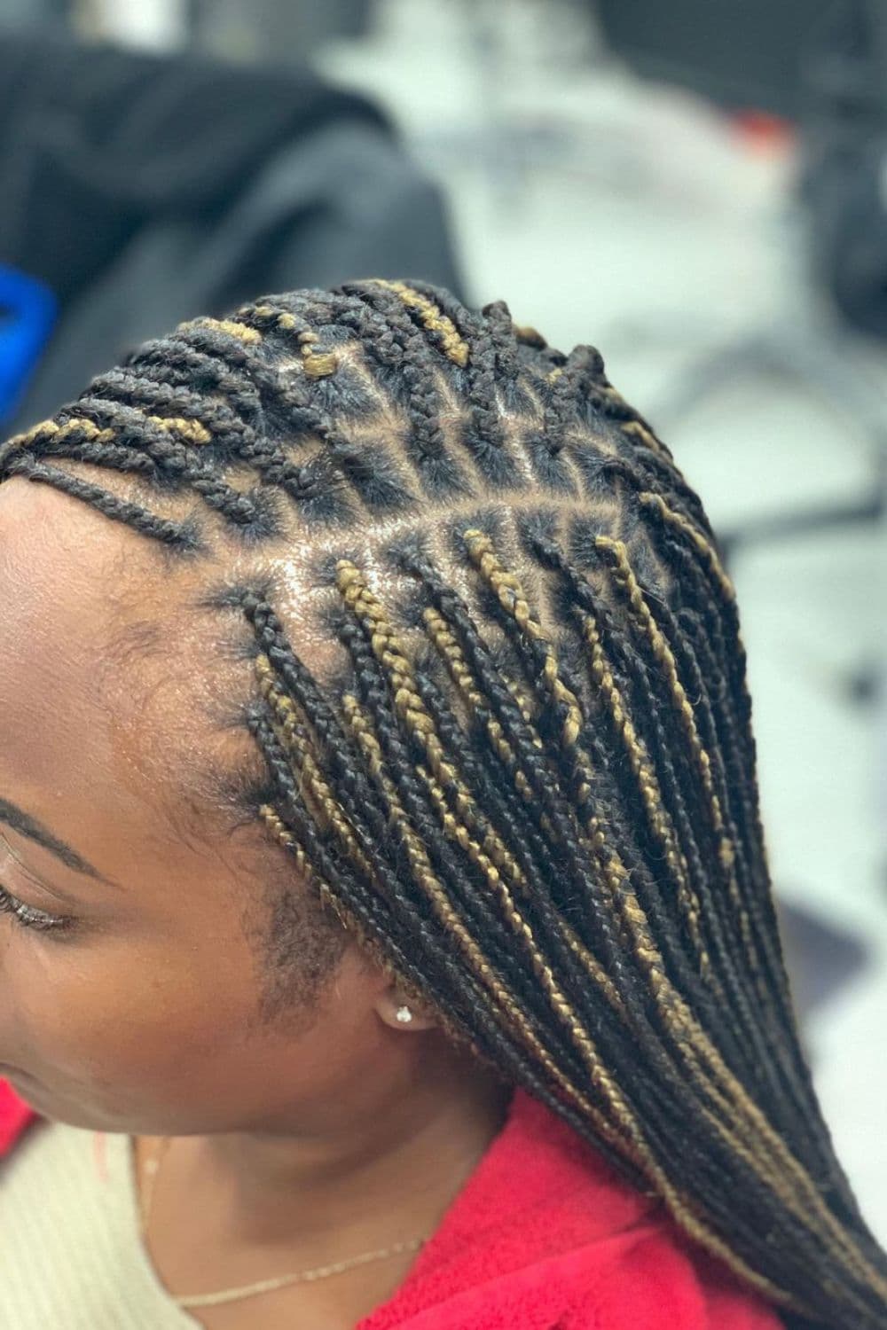 Close-up shot of a woman's black and blonde side-parted mini braids.