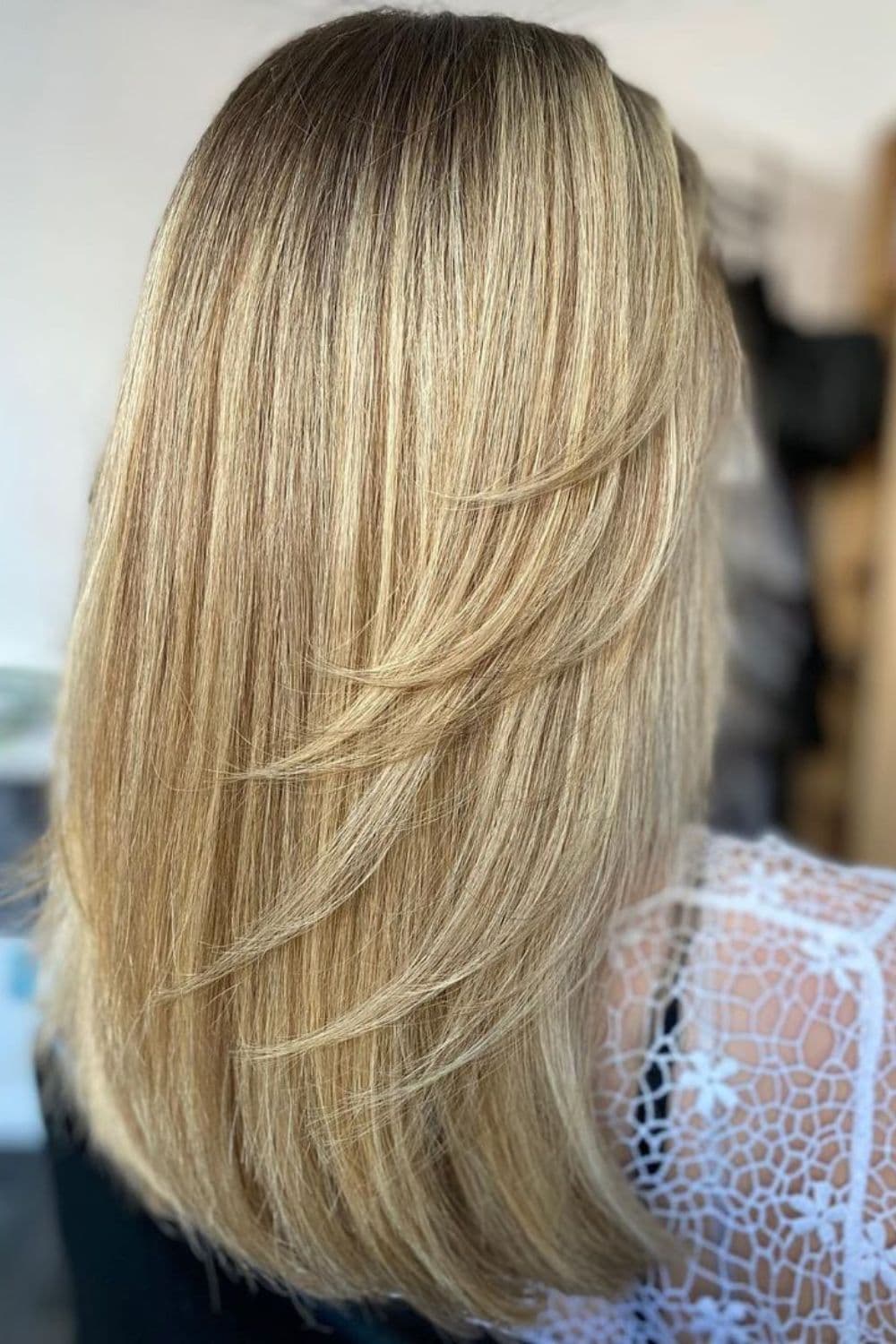 Back of a woman with long, blonde side-swept layers.