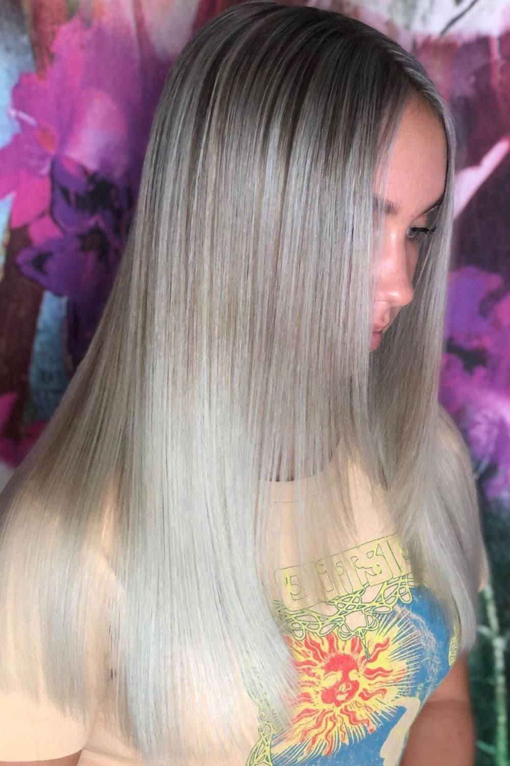 Side view of a woman with long, sleek, straight and blonde front layers.