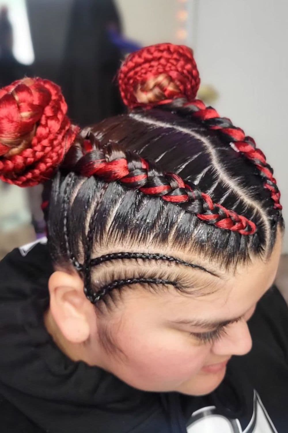 A woman with red and black space buns with cornrows.