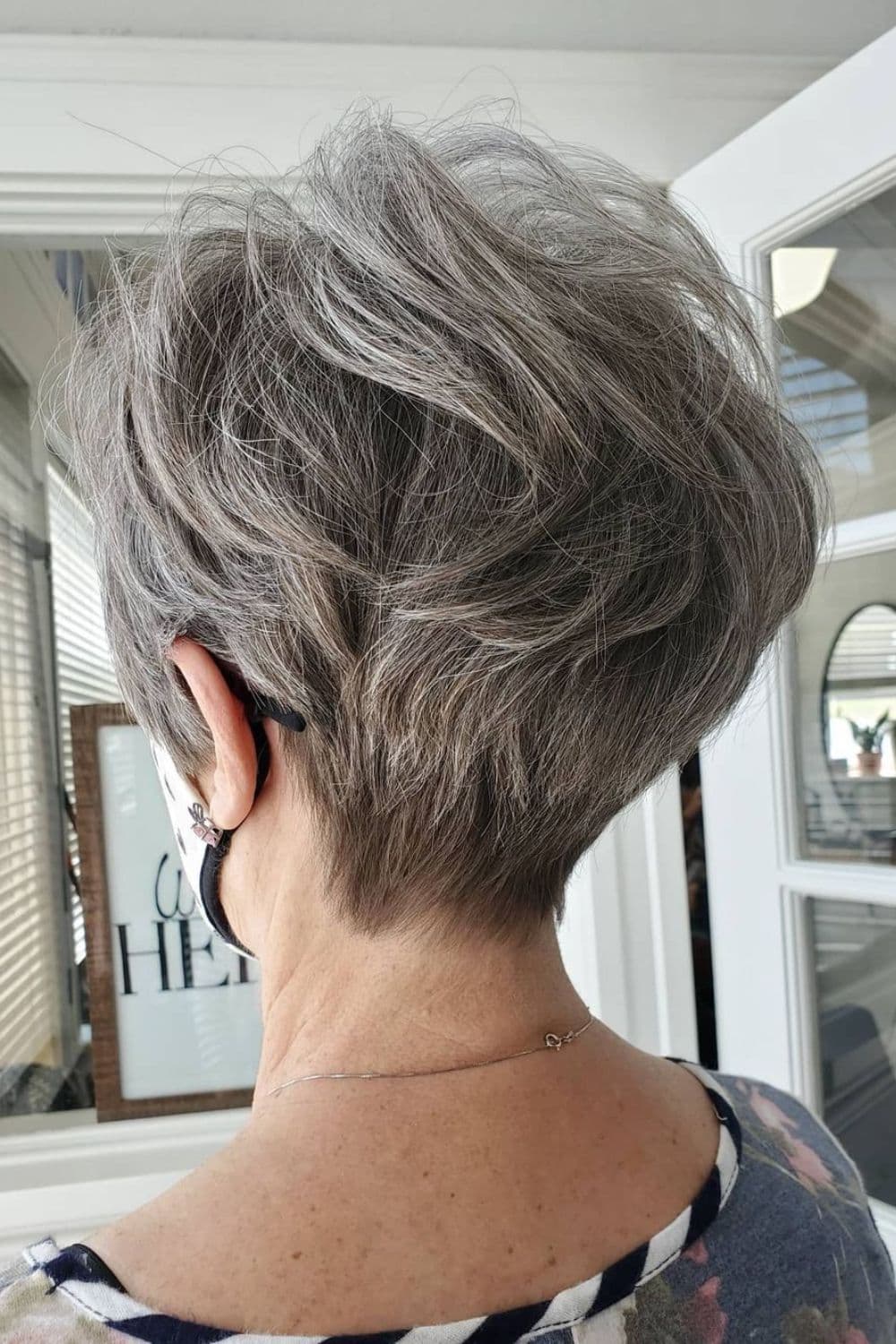 A woman's back with gray wavy tapered pixie cut.
