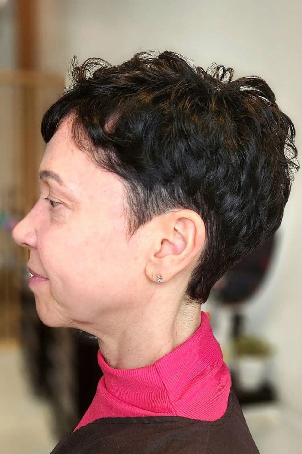 Side view of a woman with black wavy textured pixie cut.