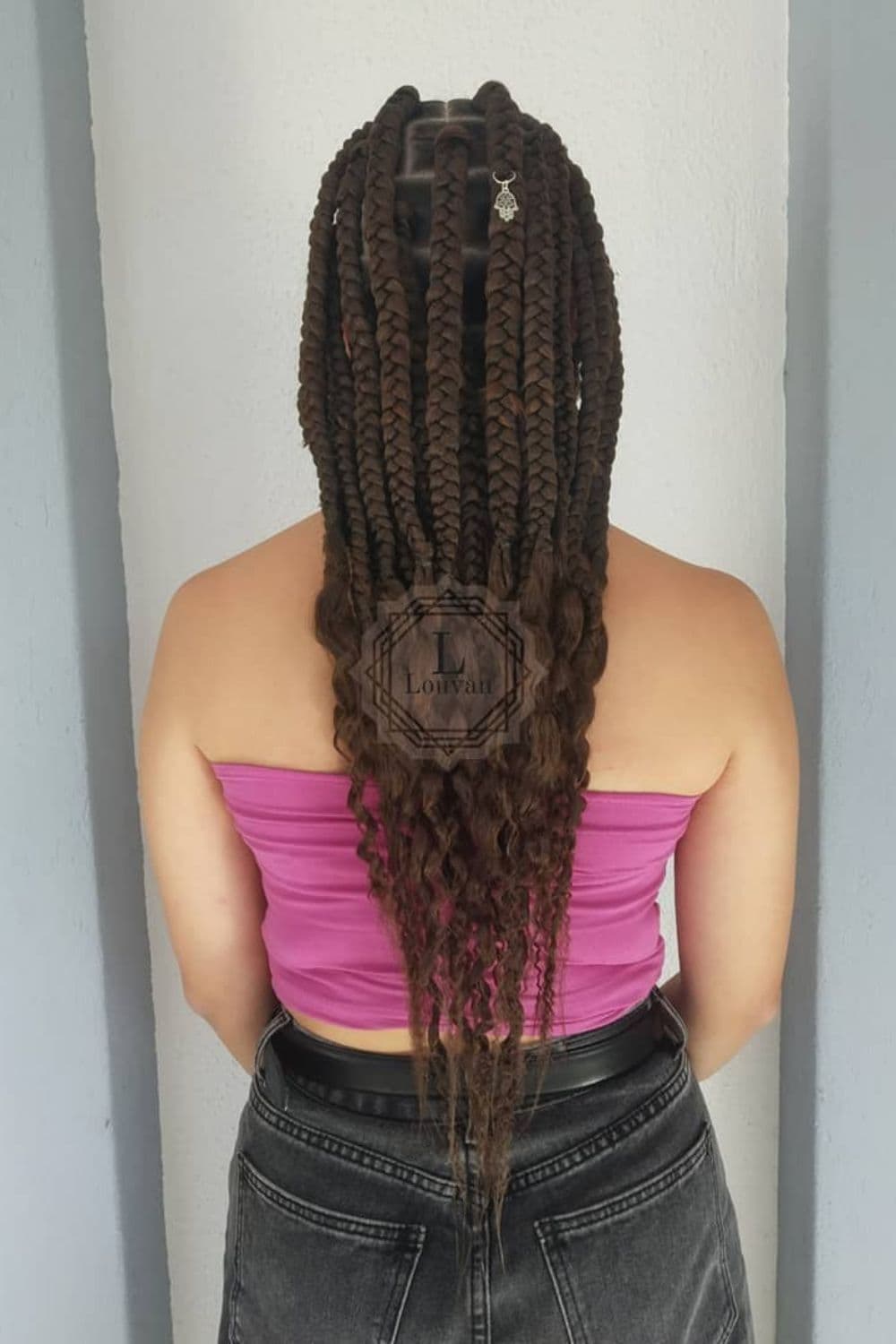 A woman in a pink tube top with brown thick box braids with curly ends.
