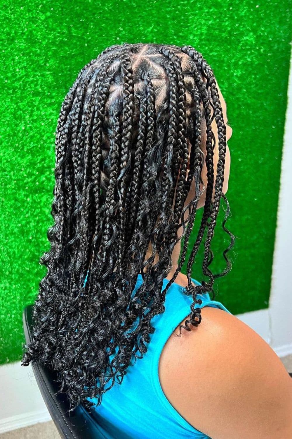 Side view of a woman with black triangle part box braids with curls
