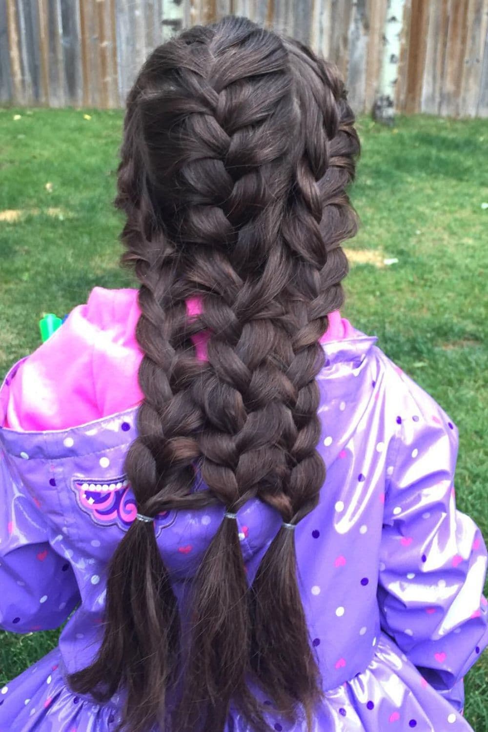 A girl wearing a purple jacket with triple French braids.