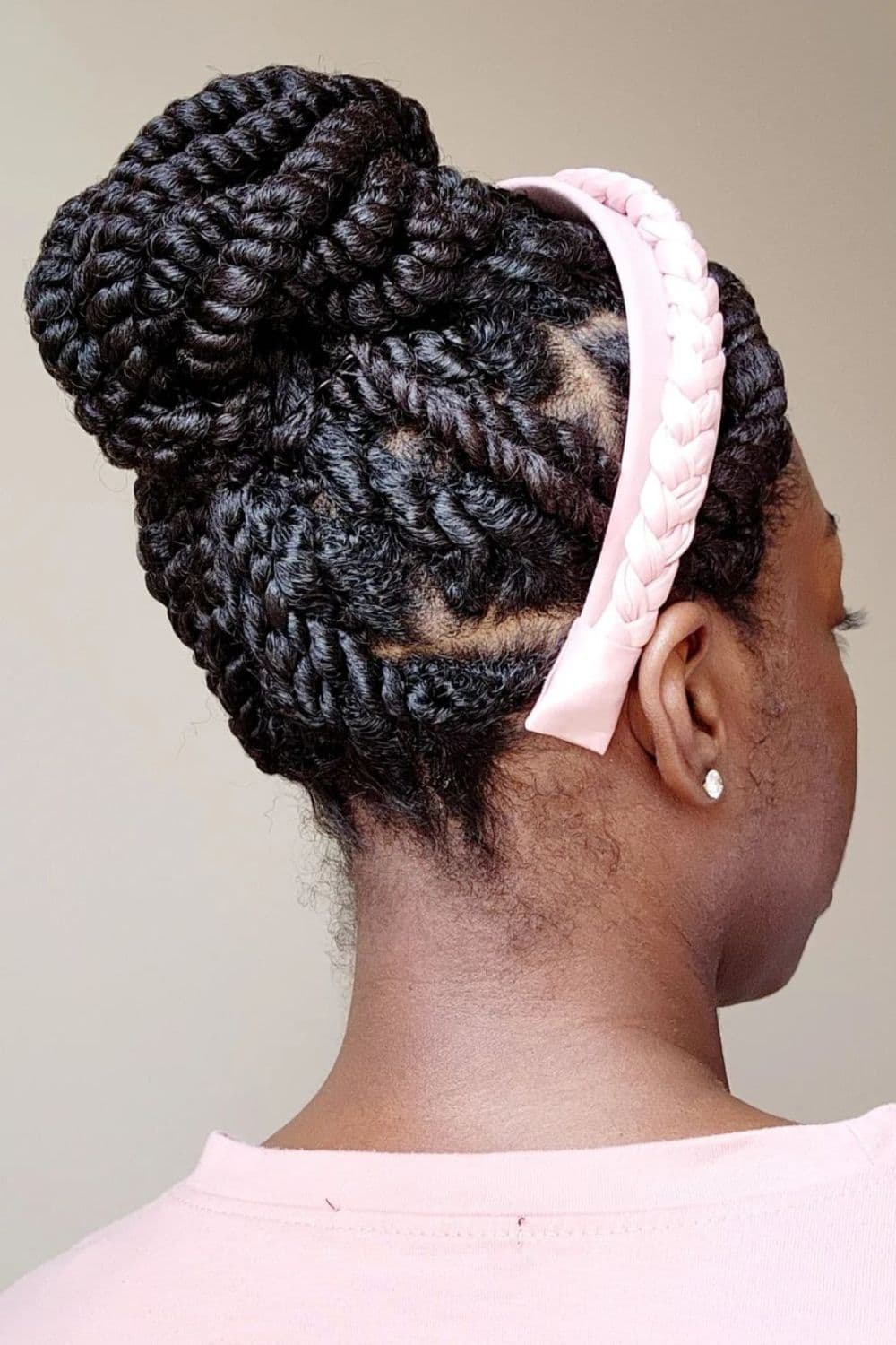 A woman wearing a pink head band with a twisted updo.
