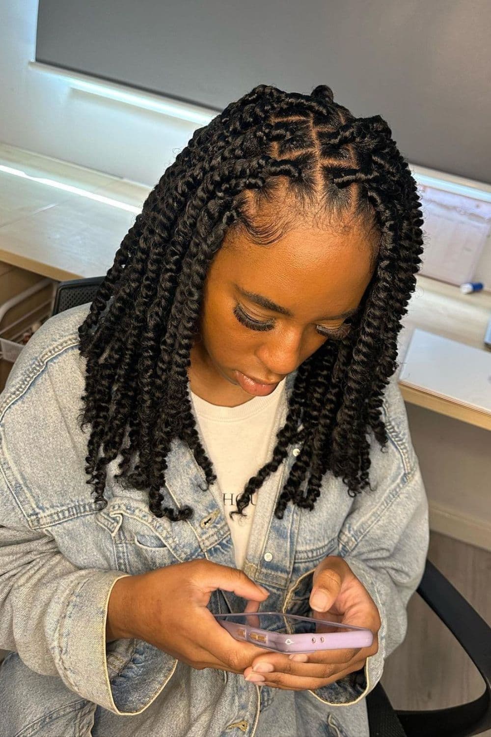 A woman with twists on medium hair looking at her phone.