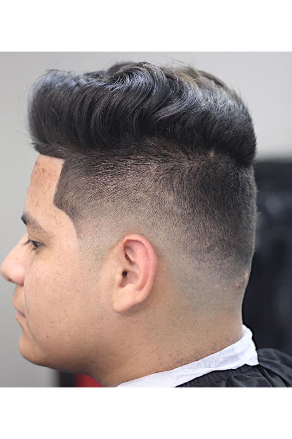 Side view of a man with undercut low taper fade.