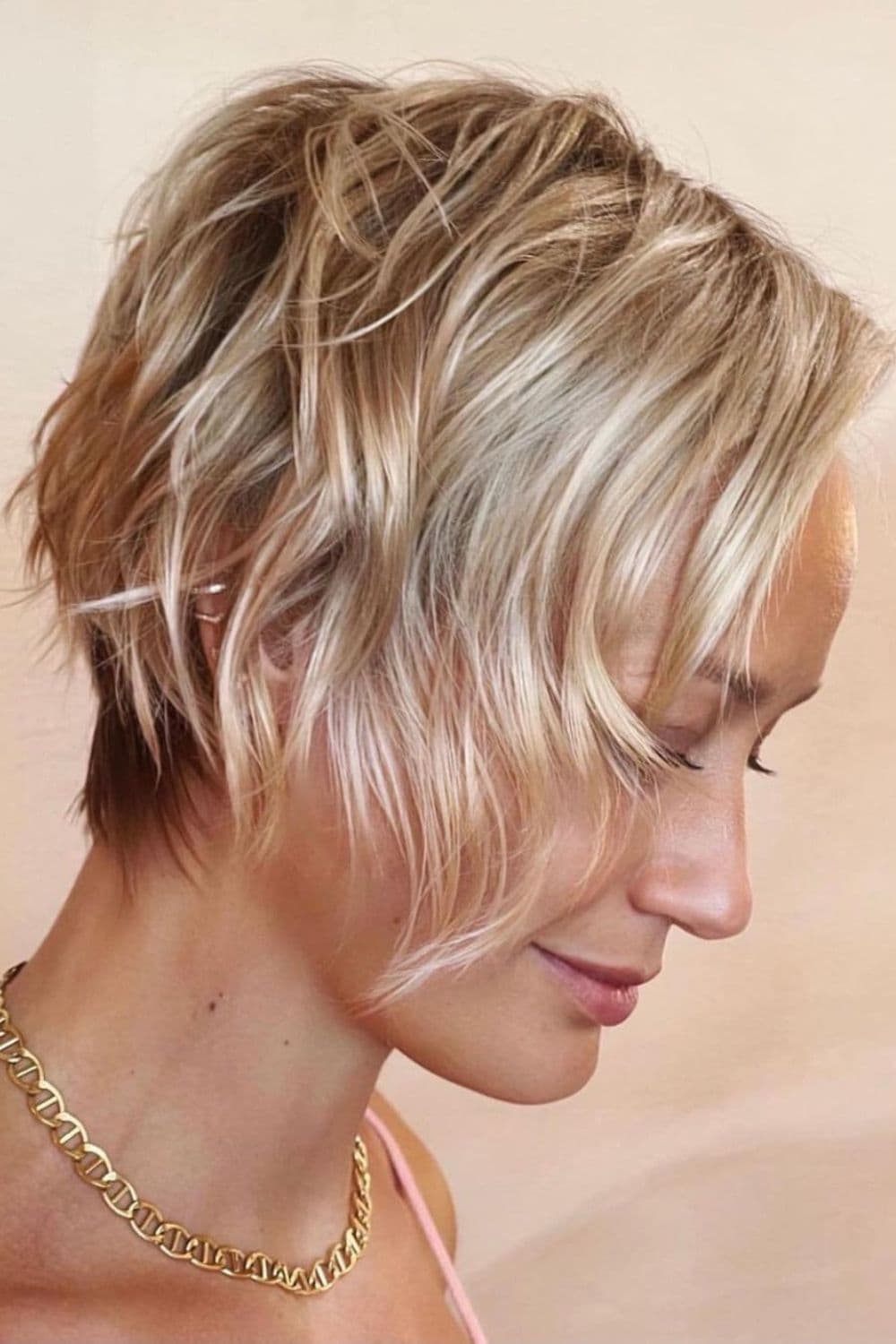 Side view of a woman with blonde wavy pixie with undercut.