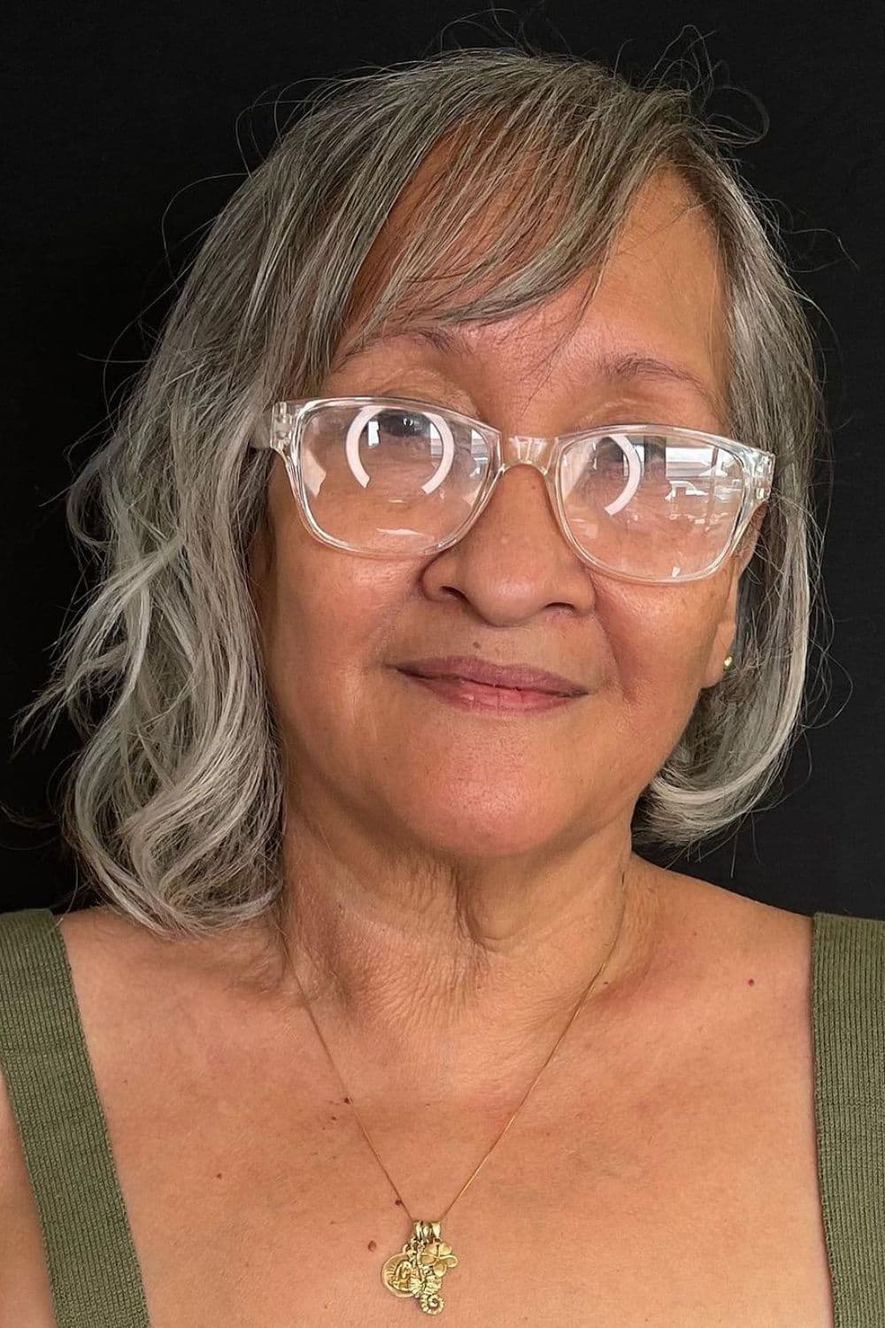 A woman wearing eyeglasses with a gray asymmetrical bob cut.