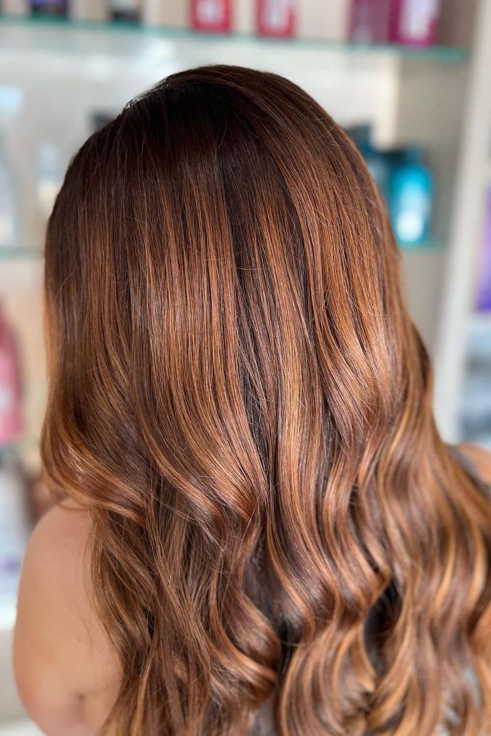 A woman with long auburn balayage.