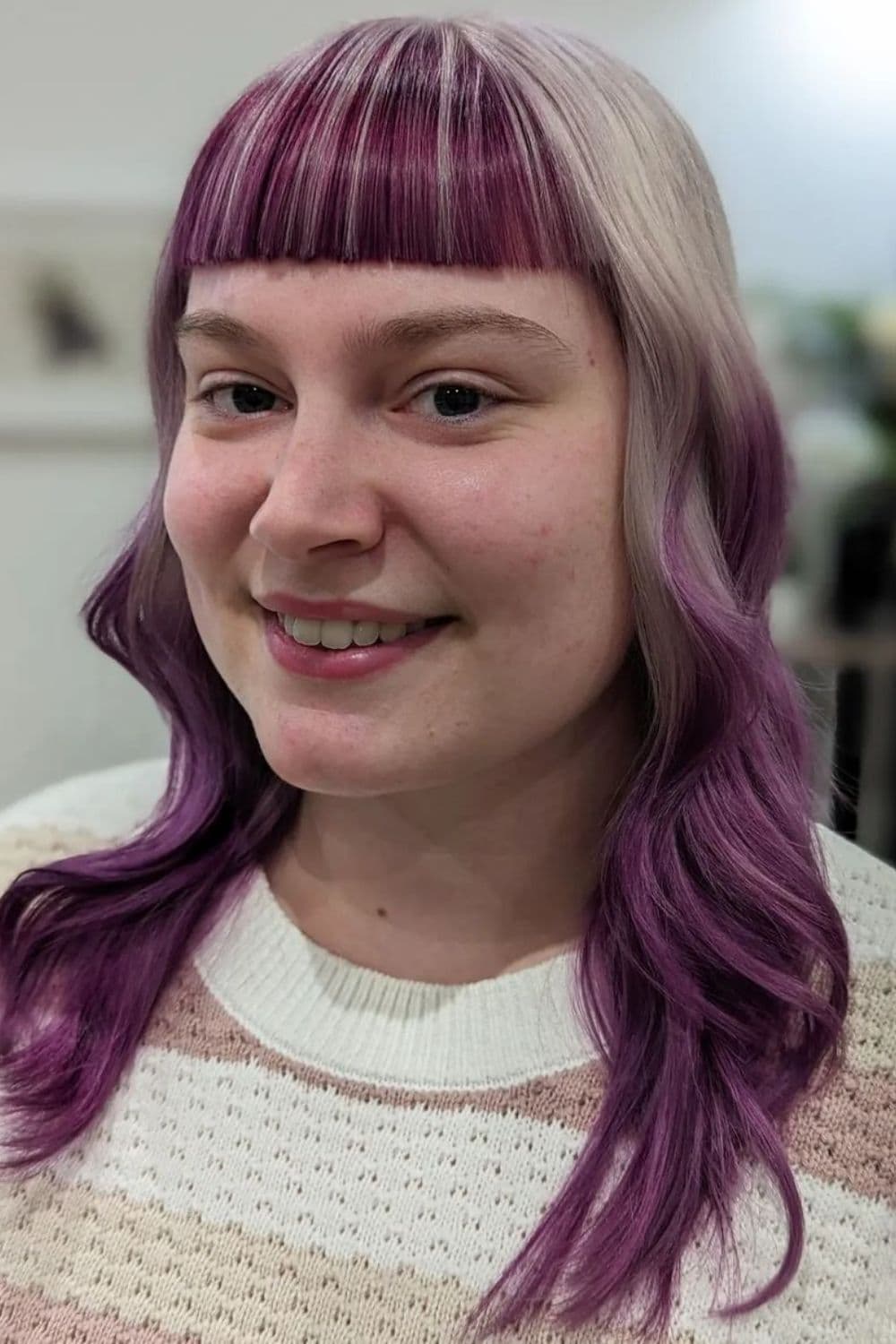 A woman with purple and blonde medium-length hair with baby bangs.