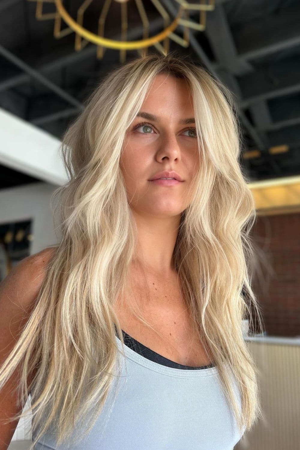 A woman with long blonde beachy middle-parted waves.