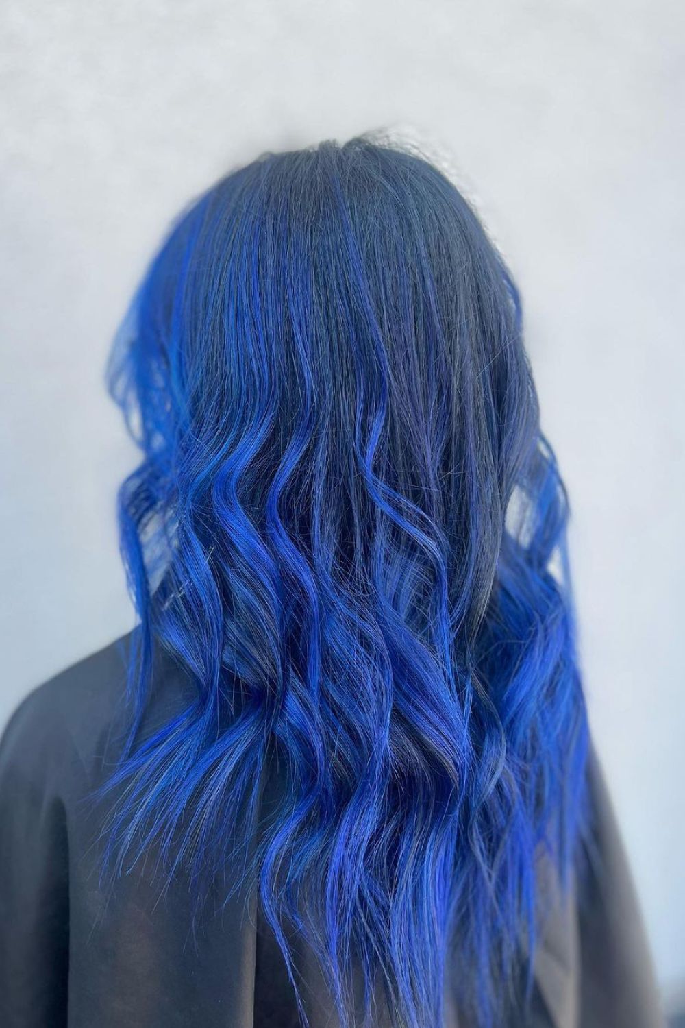 A woman with long black to blue balayage with beach waves.