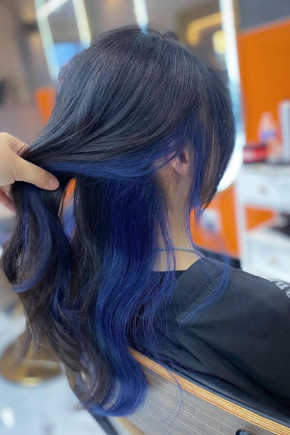 A woman with medium-length black and blue peekaboo color.