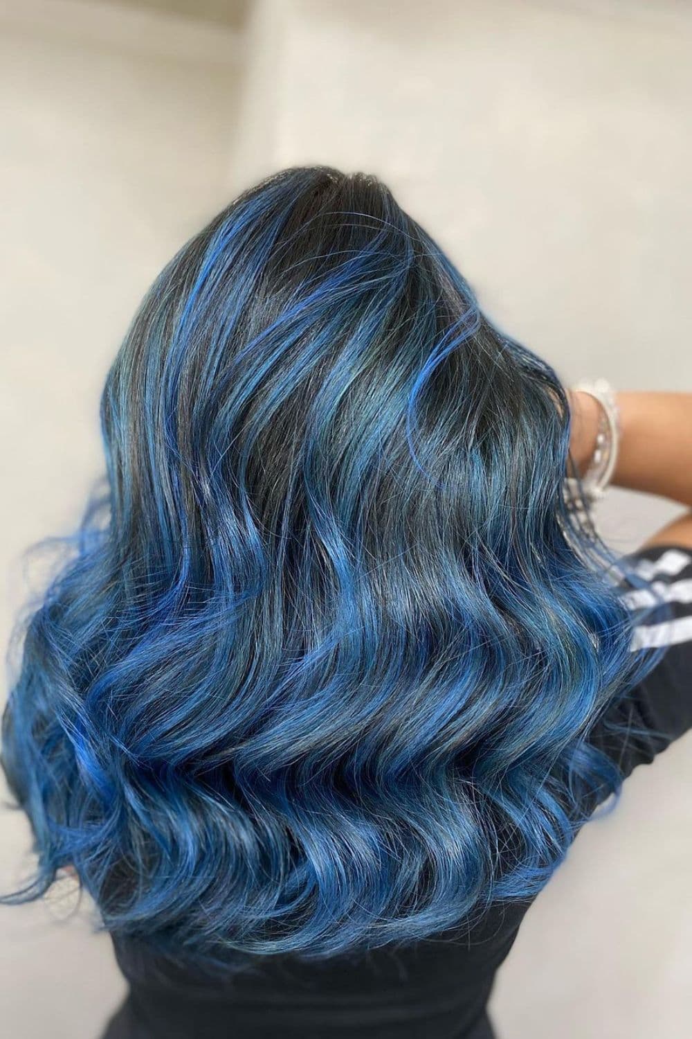 A woman with blue balayage with beach waves.