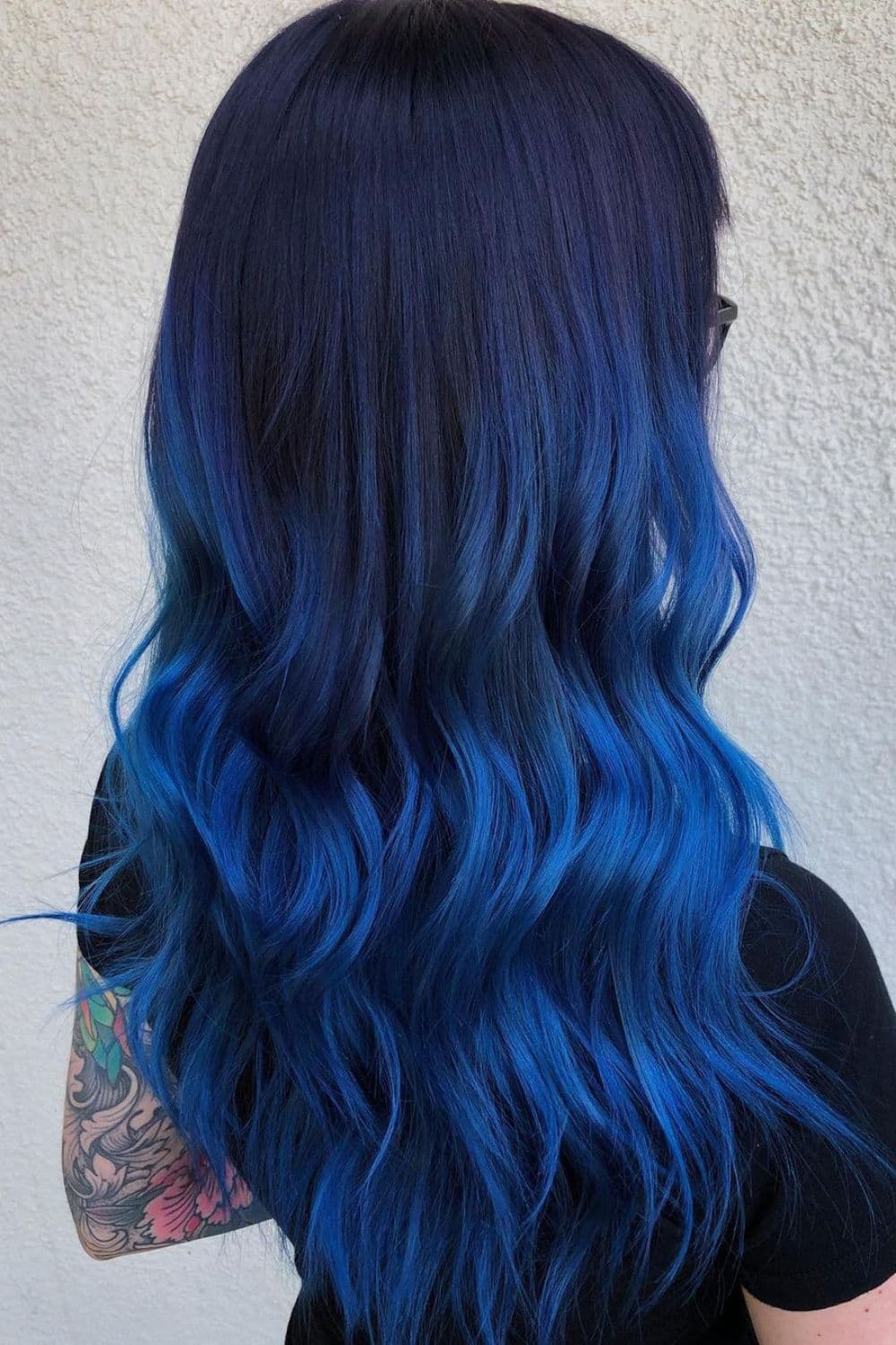 A woman with long blue-black ombre with beach waves.