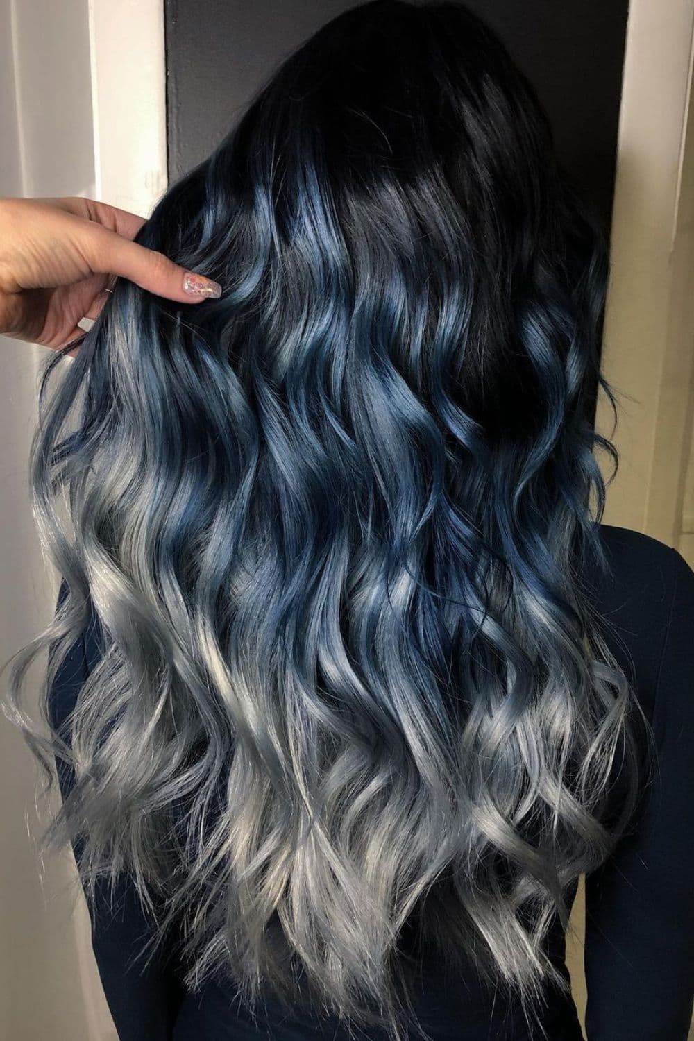 A woman with blue-black to silver ombre with big curls.