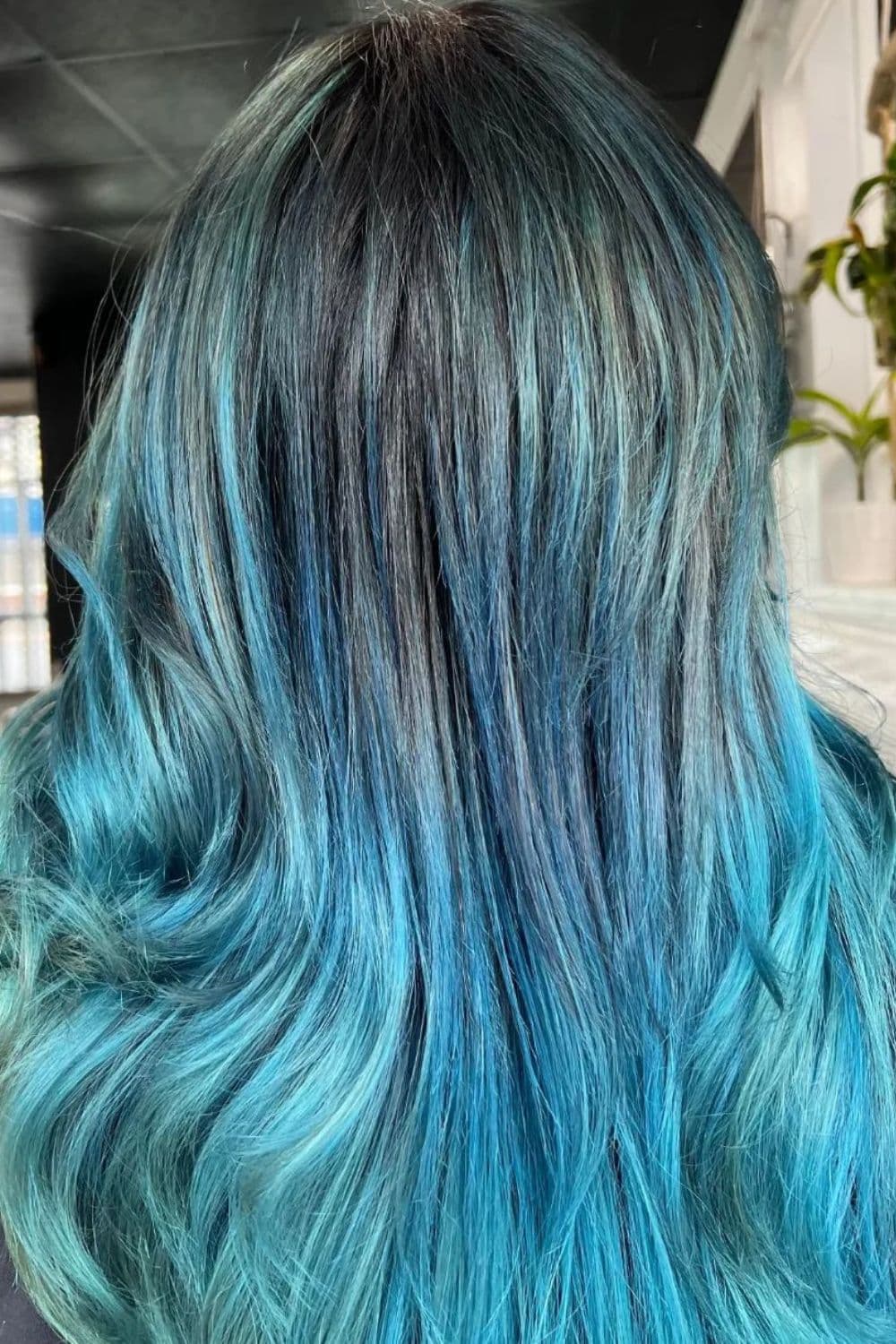 A woman with blue black to turquoise ombre hair.