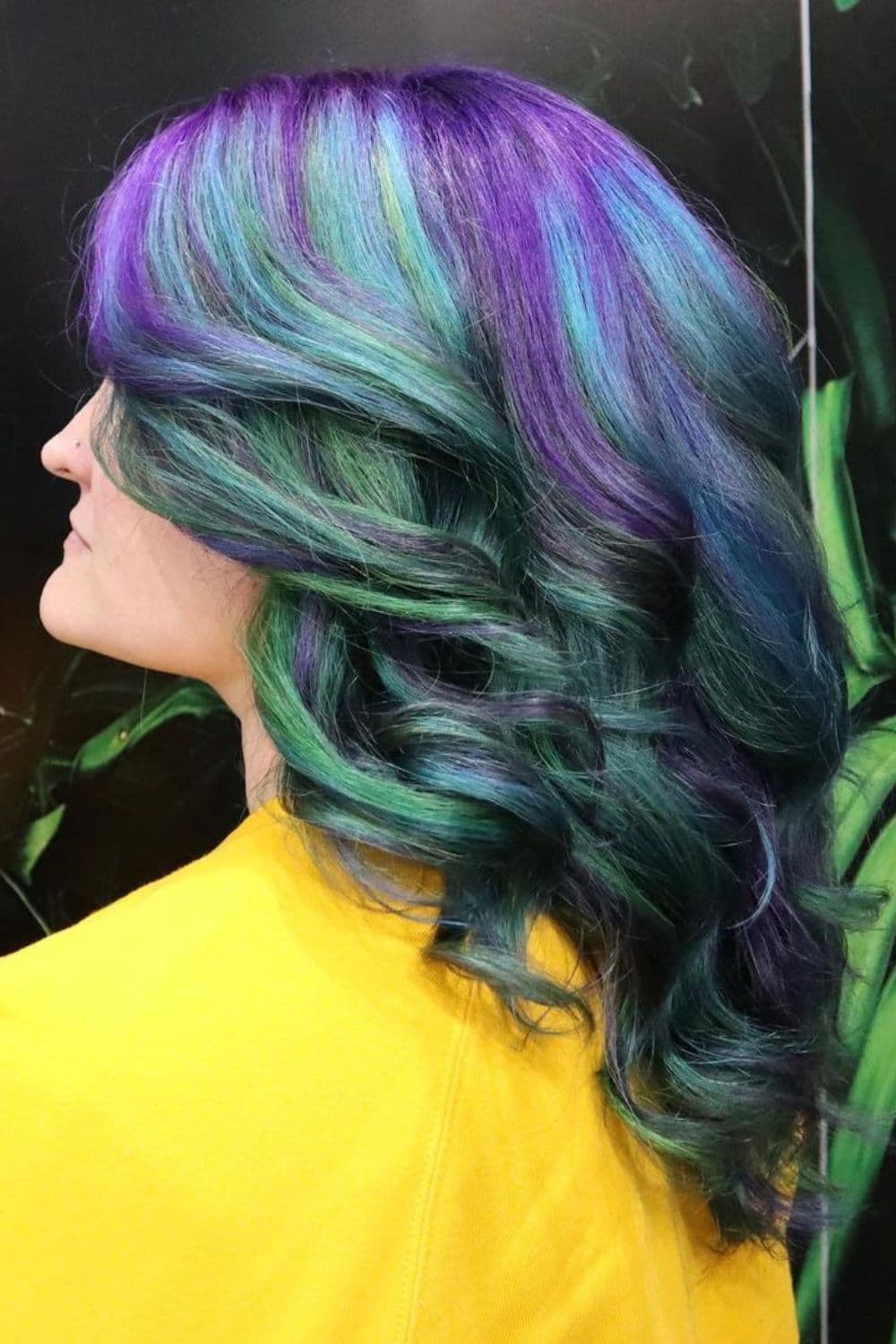 A woman with blue, green and purple hair with big curls.