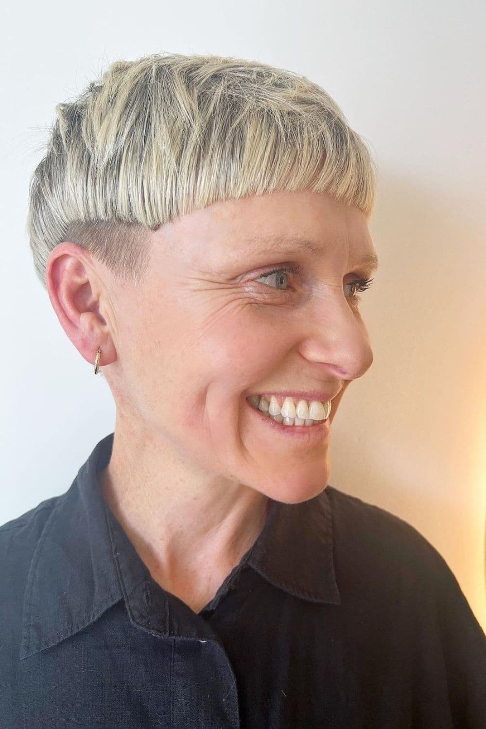 A woman with a blonde bowl cut taper fade.
