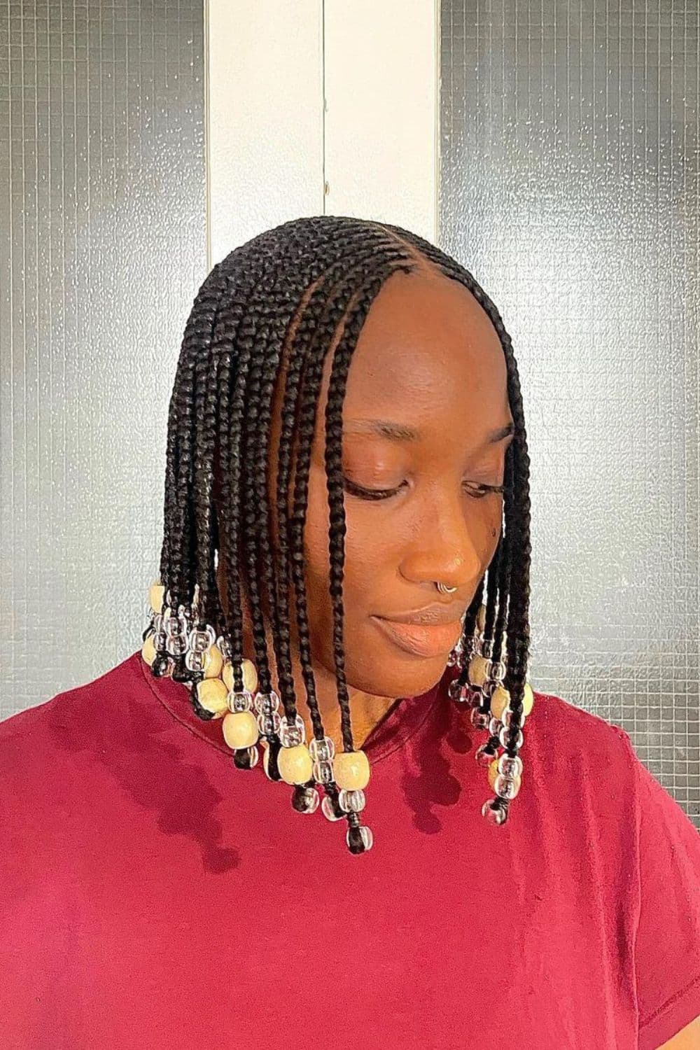 A woman with a black braided bob with beads.