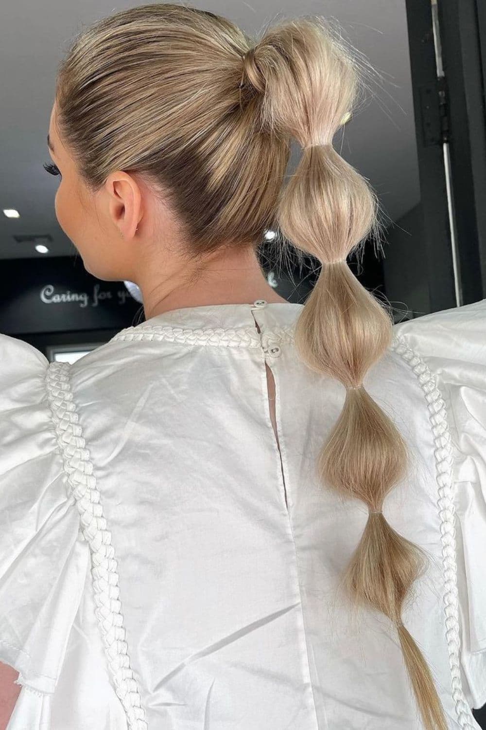A woman with a blonde high bubble ponytail.