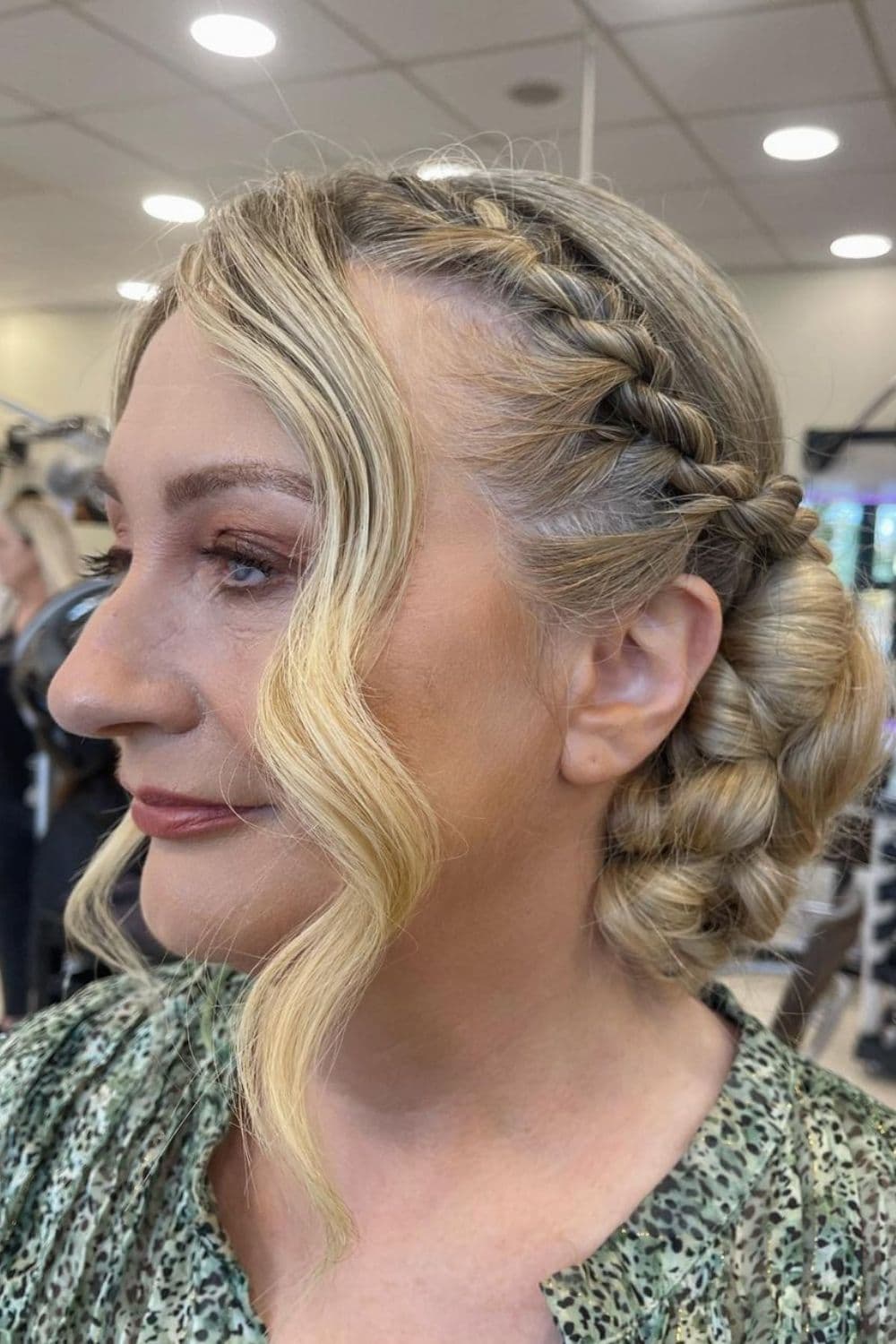 A woman with a blonde low bun with side twists.