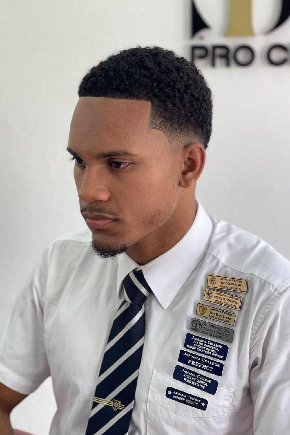 A man wearing a white polo shirt and striped necktie with buzzed low taper fade.