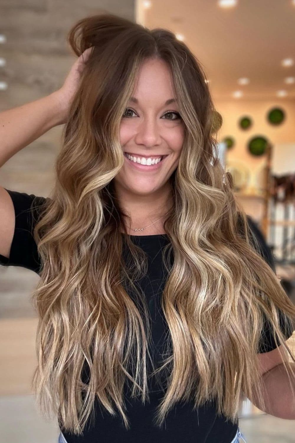 A woman with long caramel balayage with beach waves.